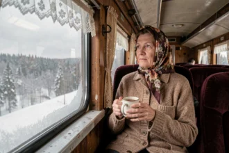 Passagère dans un compartiment du Transsibérien regardant le paysage enneigé de la taïga par la fenêtre
