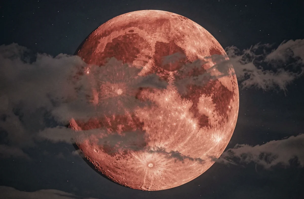 Gros plan de la lune rouge partiellement voilée par des nuages fins, surface lunaire détaillée avec cratères visibles en teintes cuivrées